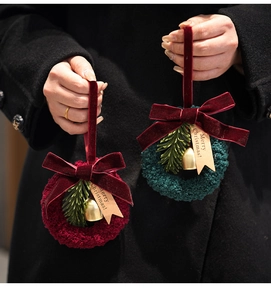 Detail of Christmas wreath ornaments with velvet bows, bells, and Merry Christmas tags