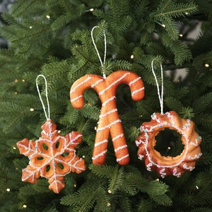 Three-piece set of foam Christmas gingerbread ornaments hanging on a festive tree branch