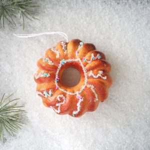 Detailed top view of realistic donut ornament with icing and sprinkles on fake snow