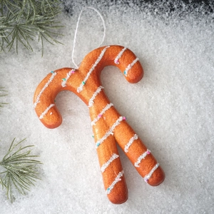 Detail of gingerbread candy cane ornament with icing texture on snowy background