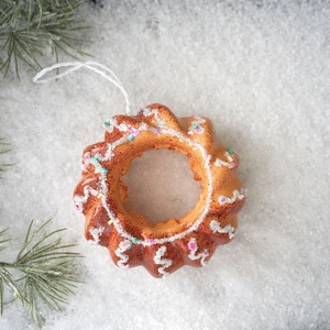 Macro shot of foam Christmas ornament in cake shape with white frosting and colorful sprinkles