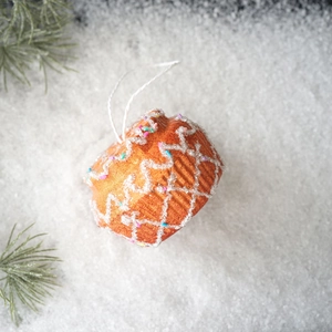 Detailed view of cupcake-shaped Christmas ornament with white frosting on a snowy background