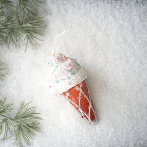 Close-up of ice cream cone Christmas ornament with white glitter snow on pine branches
