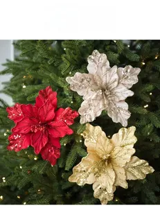 Macro detail of velvet glitter poinsettia flowers hanging on a glowing Christmas tree