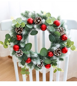 Macro detail of snow-flocked pine needles, red ornaments and eucalyptus on Christmas wreath