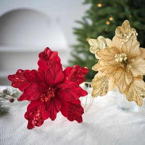 Red and gold velvet artificial Christmas flowers with glitter on festive backdrop