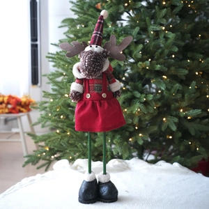 Standing Christmas reindeer doll in red plaid outfit with green legs by a festive tree