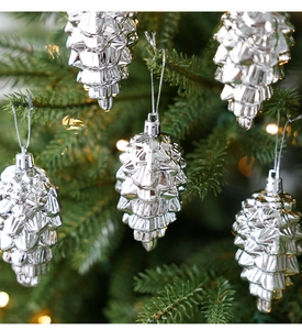 Close-up of silver pinecone Christmas ornaments with glossy finish hanging on green tree
