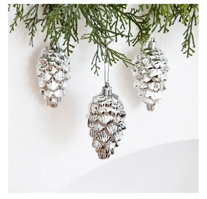 Close-up of three silver pine cone ornaments hanging on green pine branches for Christmas