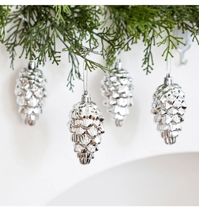 Close-up of pinecone-shaped Christmas ornaments with shiny silver finish on green pine branches