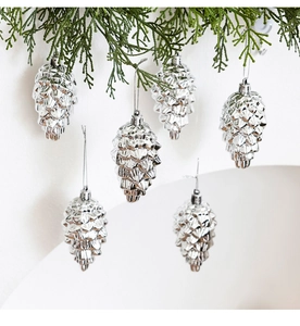 Close-up of silver pine cone ornaments hanging on green Christmas tree branches