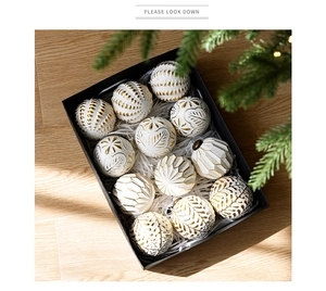 Détail de 12 boules de Noël blanches à relief doré dans leur coffret avec sapin en fond