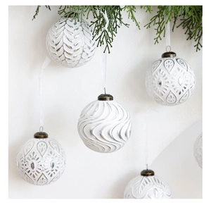 Gros plan de boules de Noël blanches 8cm avec des motifs en relief 3D et des rubans fins