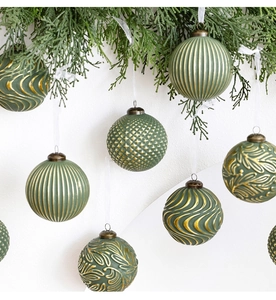 Détails de boules de Noël vert forêt avec motifs dorés et rubans de soie blancs