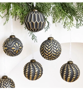 Vue détaillée de boules de Noël vintage noir et or suspendues à des branches de sapin vert