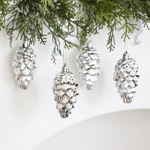 Silver pinecone Christmas tree ornaments hanging on green branches with festive glitter