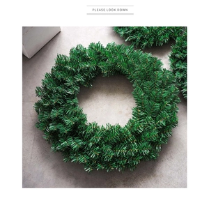 Detailed view of dense dark green PVC pine needle Christmas wreath on a grey texture