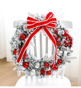 Detail of flocked Christmas wreath with red berries, silver ornaments, and velvet bow