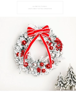 Detail of flocked Christmas wreath with red bow, berries and festive ornaments