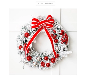 Close-up of flocked Christmas wreath with red berries, silver ornaments and a large bow