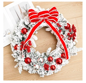 Detail of frosted Christmas wreath with red berries and a large striped bow on wood floor