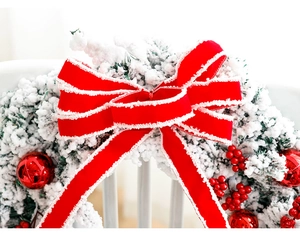Detail of red velvet bow with white lace trim on snowy Christmas wreath decoration