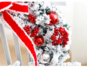 Close-up of frosted Christmas garland with red bows, berries and shiny ornaments