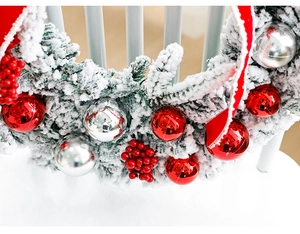 Detailed view of snowy Christmas wreath with red berries, silver ornaments, and ribbon