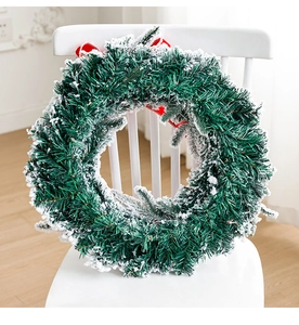 Detail of flocked Christmas wreath with snow effect and red ribbon on a white chair