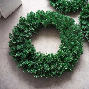 Lush green PVC pine needle Christmas wreath on a modern grey textured background