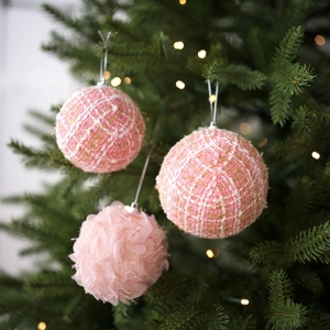 Pink tweed and plush fabric Christmas ball ornaments set hanging on a lit Xmas tree