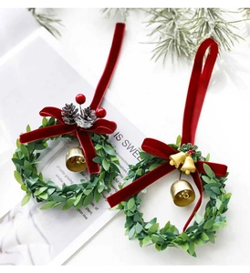 Detail of mini Christmas wreaths with red velvet bows and festive gold bells or pine cones