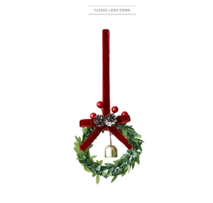 Close-up of Christmas wreath with red velvet bow, pine cones, and a gold metal bell