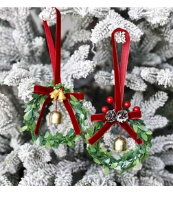 Close-up of Christmas wreaths with red velvet bows and gold bells on a snowy tree branch