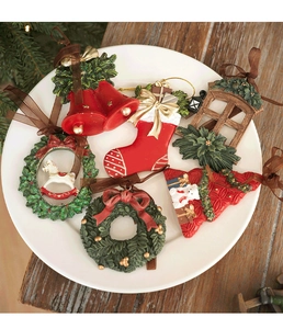 Close-up of resin Christmas ornaments set including bell and stocking on white plate
