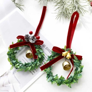 Christmas wreath pendants with red velvet bows, pine cones, and gold bells on white background