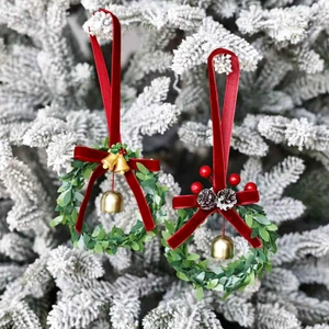 Christmas mini wreaths with red velvet bows and gold bells on snowy pine branches