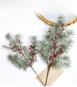 Détail de branches de pin givrées avec baies rouges, pommes de pin et cloches festives
