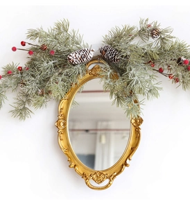 Détail d'un miroir ovale doré orné avec branches de pin et baies rouges de Noël festives