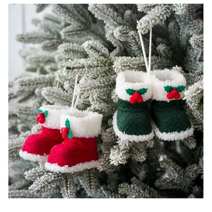 Detailweergave van rode en groene kerstlaarsjes hangend aan een besneeuwde kerstboom