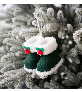 Detail van groene gewatteerde kerstlaarsjes met imitatiebont aan besneeuwde takken