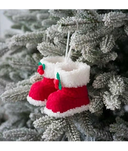 Detailopname van rode gebreide kerstlaarzen met bontrand op besneeuwde dennentakken