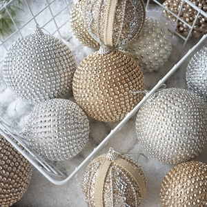 Close-up of champagne foam Christmas balls with glitter and pearls in a basket