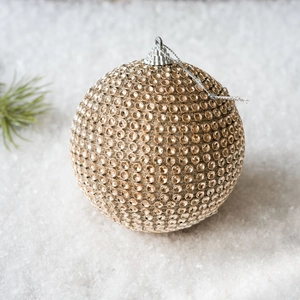 Sparkling champagne gold Christmas ball ornament with rhinestones on a snowy background