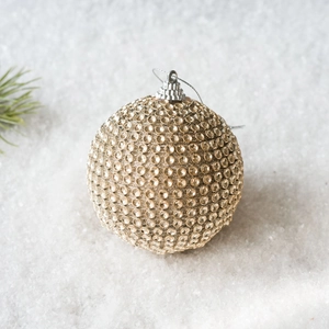Close-up of luxury champagne gold rhinestone Christmas ball ornament on white snow