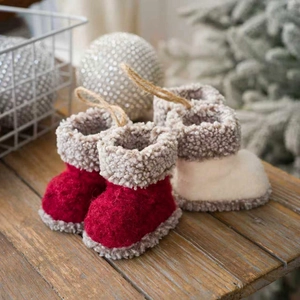 Creatieve vilten kerstlaarzen in rood en wit hangend als decoratie in de feestelijke boom