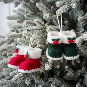 Rode en groene kerstlaarsjes met imitatiebont hangend aan besneeuwde dennentakken