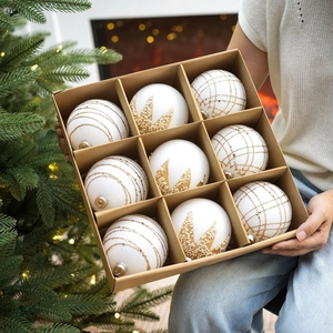 Gros plan de neuf boules de Noël blanches et dorées dans une boîte cadeau