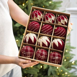 Détail de boules de Noël en velours bordeaux avec paillettes dorées et perles