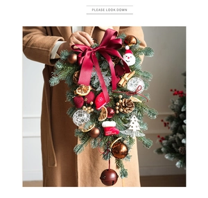 Detail of Christmas swag with Santa doll, red bow, pine cones, and bells on pine needles